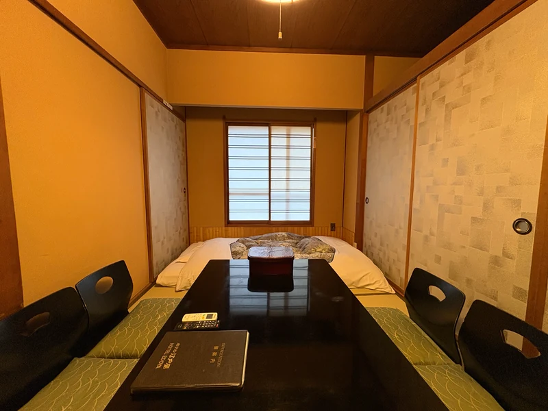 座卓と座椅子の向こうに布団を整えた江戸屋の和室