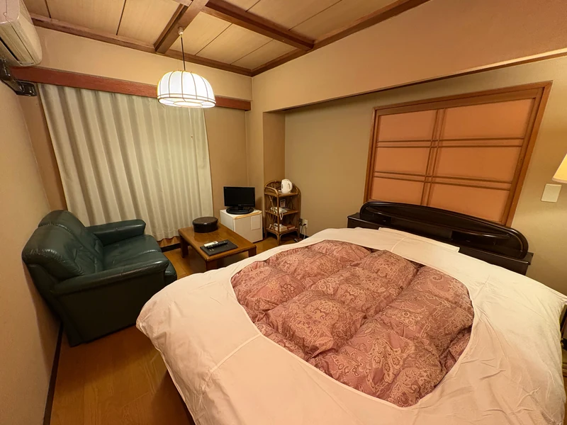 ベッドと窓際のソファを備えた江戸屋の洋室