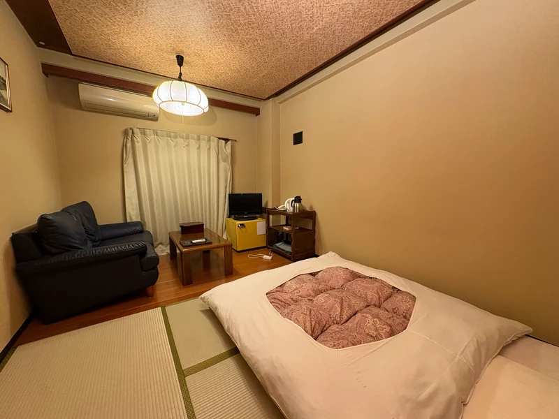 畳に布団を敷き、窓際にソファを置いた江戸屋の和室
